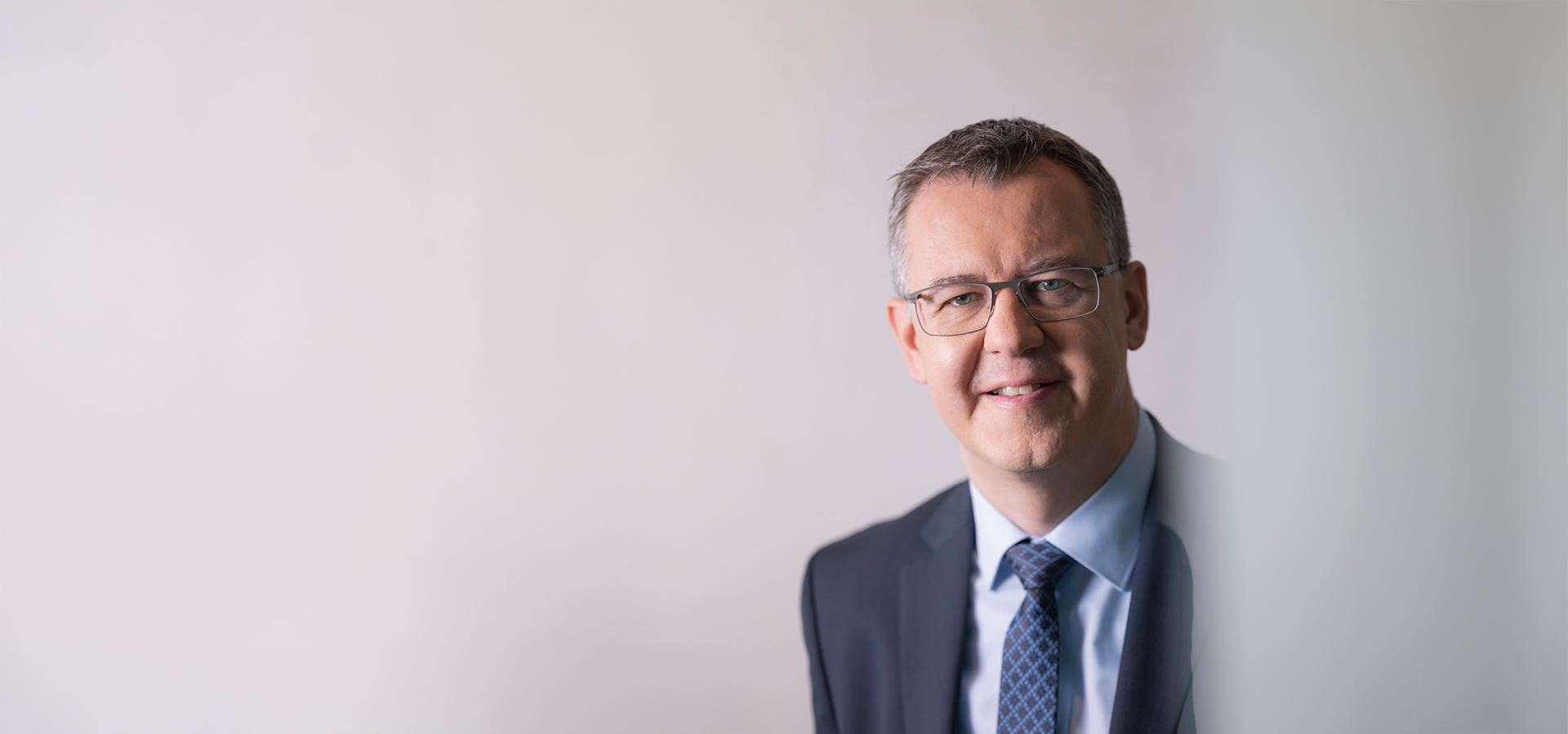 Christoph Winterhalter im Anzug vor neutralem Hintergrund, spricht über Green IT und KI.