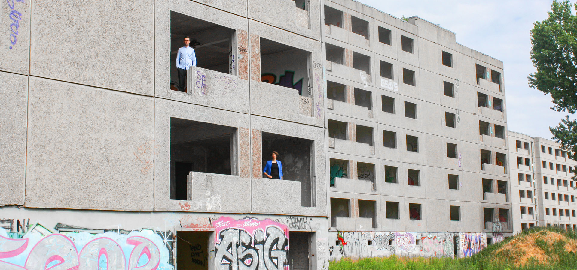 Zwei Personen stehen in einem verlassenen Gebäude mit Graffiti an den Wänden