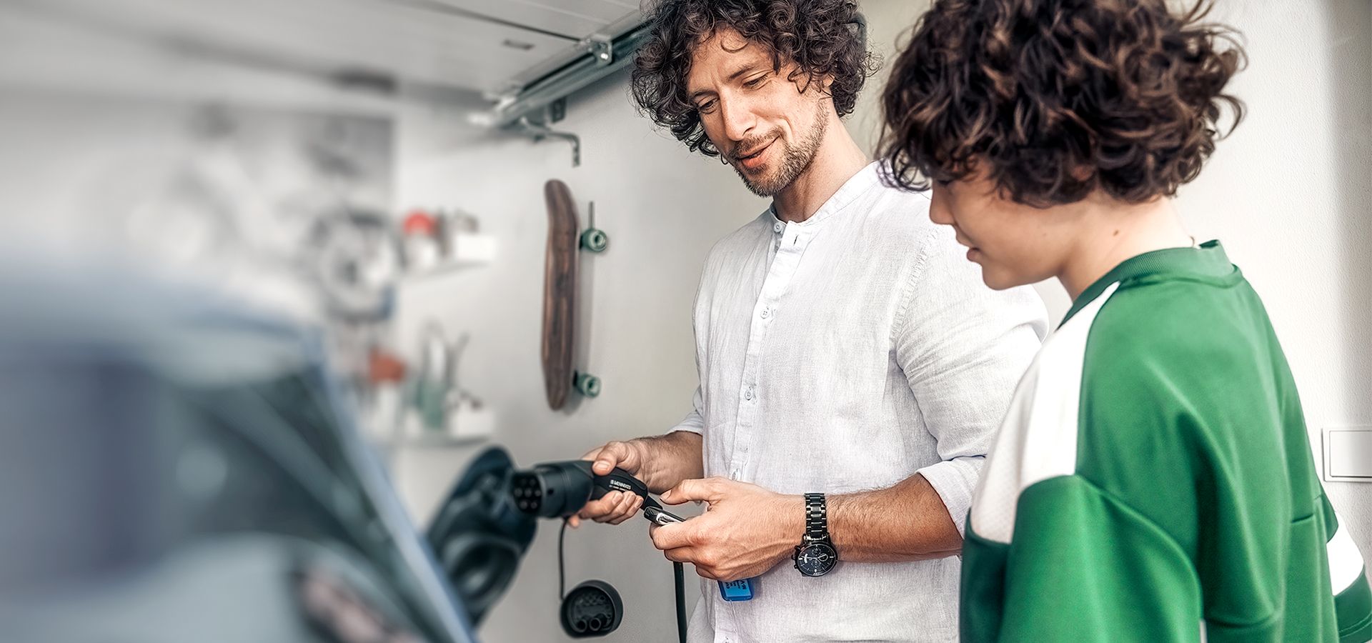 Mann lädt ein Elektroauto in der Garage mit Mennekes Ladestecker Typ 2 nach DIN-Norm